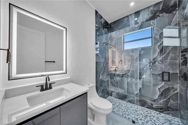Bathroom featuring vanity, toilet, and a tile shower