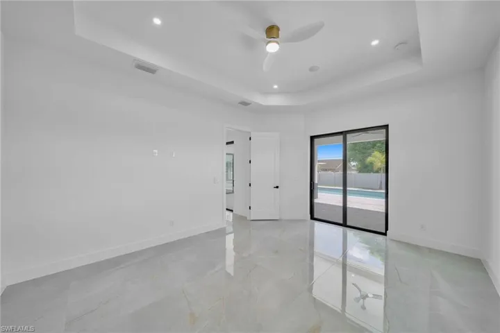 Empty room featuring a tray ceiling and ceiling fan