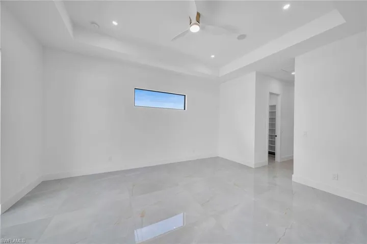Empty room with ceiling fan and a tray ceiling