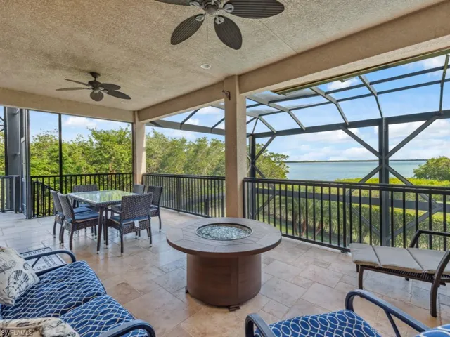 View of patio featuring a lanai, a water view, ceiling fan, and an outdoor fire pit