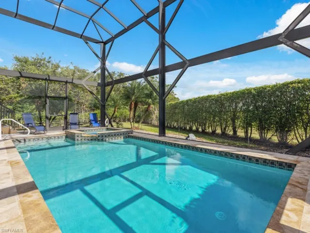 View of swimming pool with glass enclosure, an in ground hot tub, and a patio area