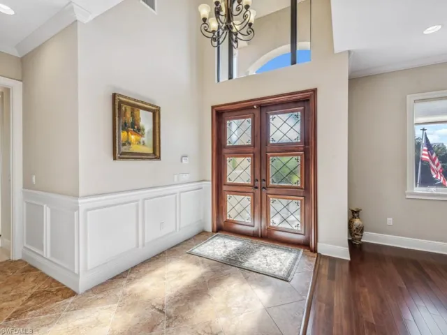 Entryway featuring hardwood / wood-style floors, crown molding, french doors, and a chandelier