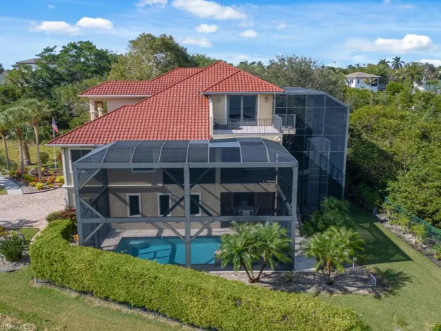Rear view of house with a balcony, glass enclosure, and a lawn