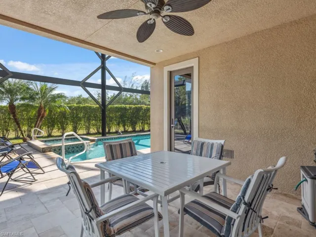 View of patio with ceiling fan, a pool with hot tub, and glass enclosure