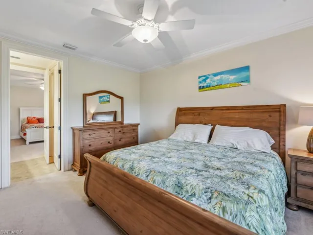 Bedroom with ceiling fan, light carpet, and ornamental molding