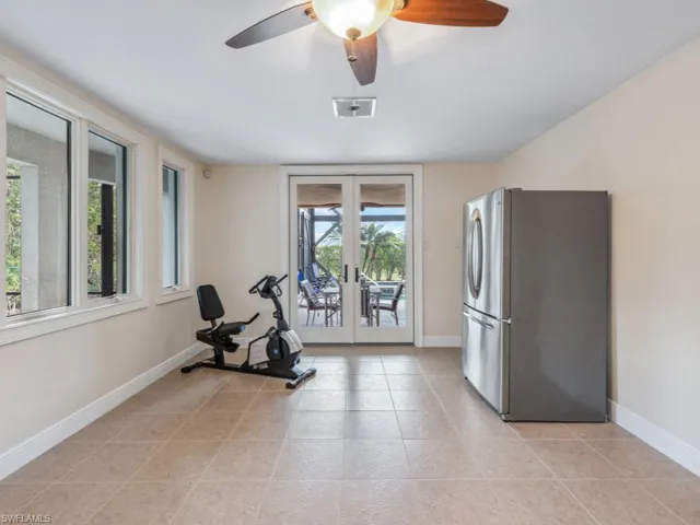 Workout area with french doors, light tile patterned floors, ceiling fan, and a healthy amount of sunlight
