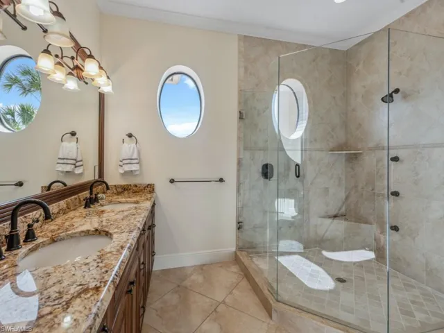 Bathroom featuring vanity, crown molding, a notable chandelier, tile patterned flooring, and a shower with shower door