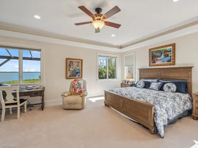 Bedroom with light carpet, ceiling fan, and ornamental molding