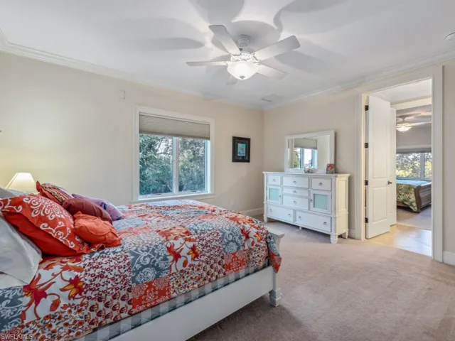 Bedroom featuring light colored carpet, ceiling fan, and crown molding