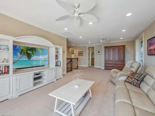 Living room featuring light colored carpet, ceiling fan, and ornamental molding
