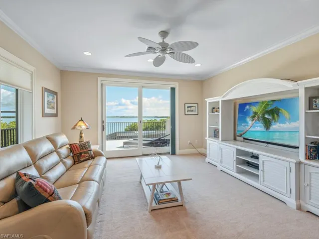 Living room with crown molding, ceiling fan, and light colored carpet