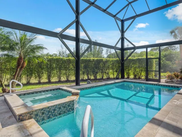 View of pool featuring glass enclosure and an in ground hot tub