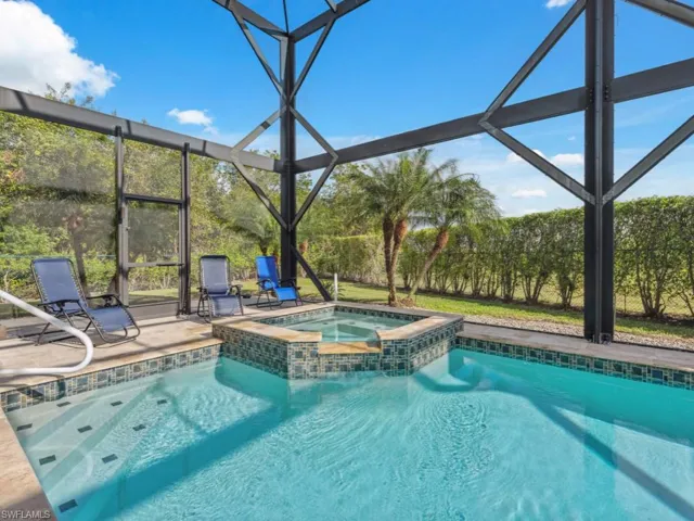 View of pool featuring an in ground hot tub, glass enclosure, and a patio area