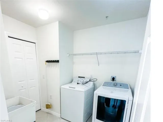 Laundry area with laundry area, washing machine and dryer, and light tile patterned floors