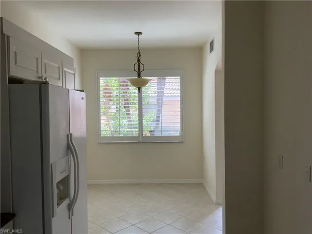 Kitchen with visible vents, baseboards, light tile patterned floors, and white fridge with ice dispenser