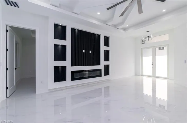 Empty room with marble tiled floors, a chandelier, recessed lighting, beam ceiling, and french doors