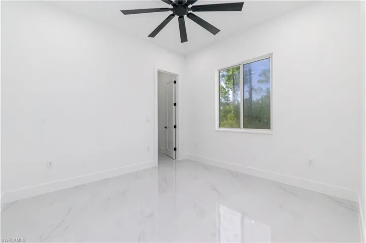 Unfurnished room featuring light marble finish floors and ceiling fan