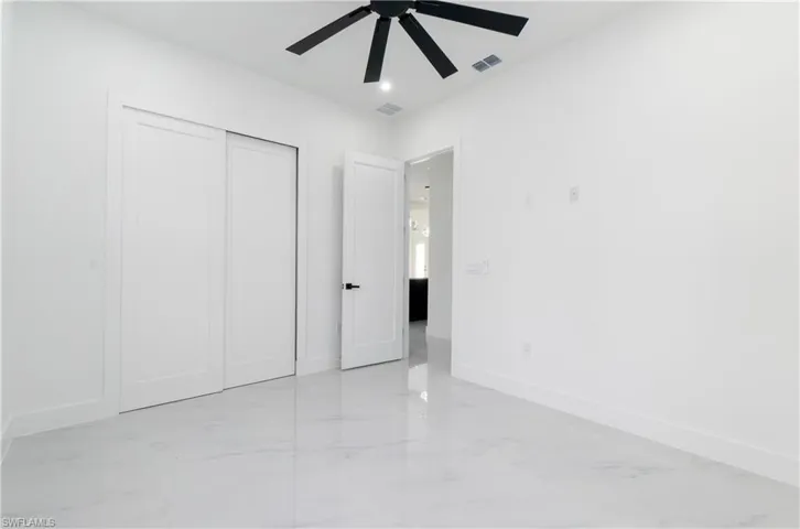 Unfurnished bedroom featuring light marble finish flooring, a closet, a ceiling fan, and recessed lighting