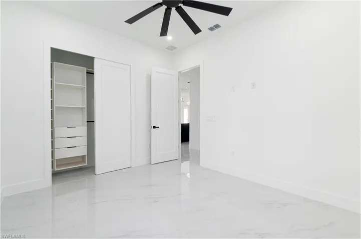 Unfurnished bedroom featuring light marble finish flooring, a closet, and ceiling fan
