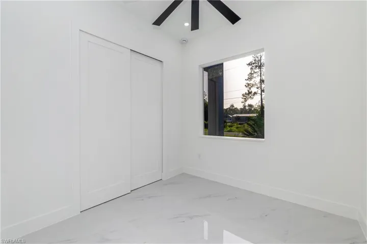 Unfurnished bedroom featuring light marble finish floors, a closet, ceiling fan, and recessed lighting