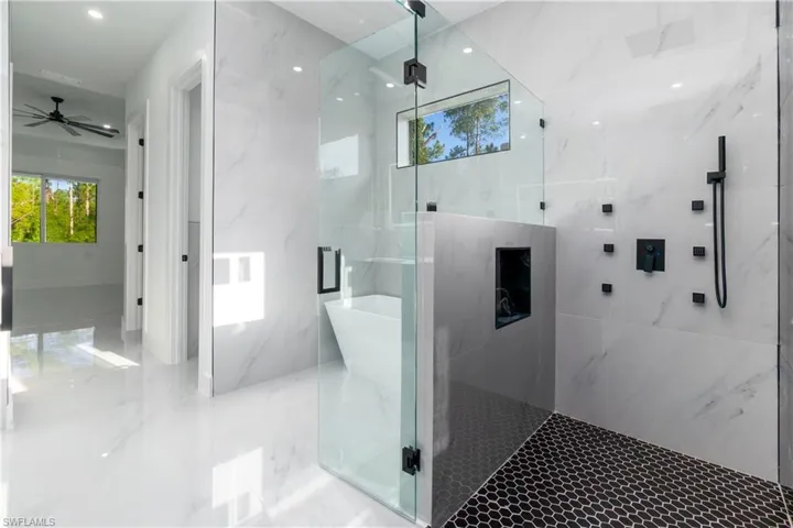 Bathroom featuring a marble finish shower, ceiling fan, marble tiled floors, and a soaking tub