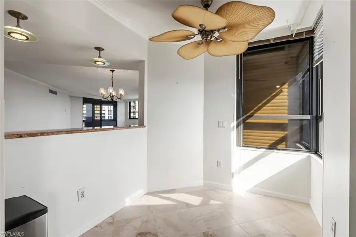 Empty room with ceiling fan with notable chandelier and ornamental molding