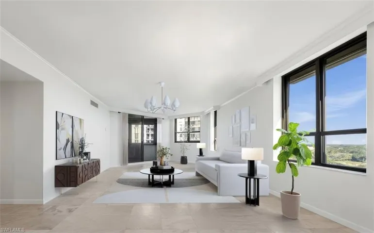Living room with plenty of natural light, ornamental molding, and a chandelier