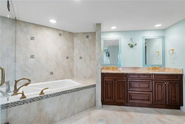 Bathroom with tile patterned flooring, vanity, tile walls, and tiled bath