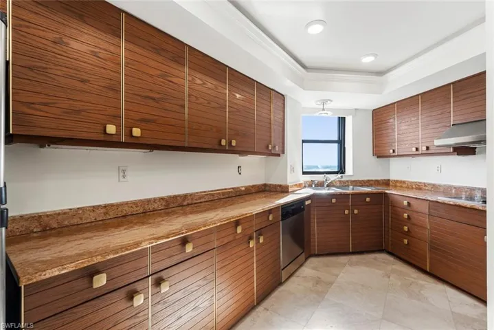 Kitchen with stone counters, dishwasher, sink, stovetop, and extractor fan