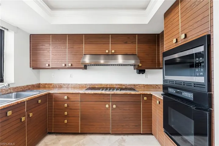 Kitchen featuring sink, a tray ceiling, ornamental molding, and black appliances