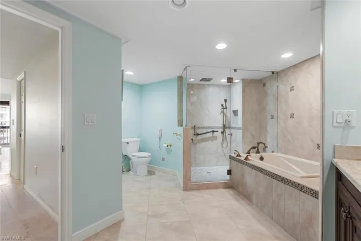 Full bathroom with toilet, tile patterned floors, vanity, and separate shower and tub