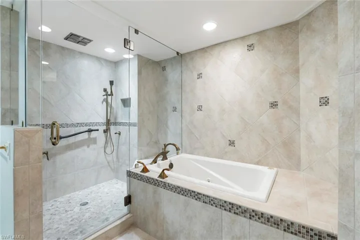 Bathroom featuring separate shower and tub and tile walls