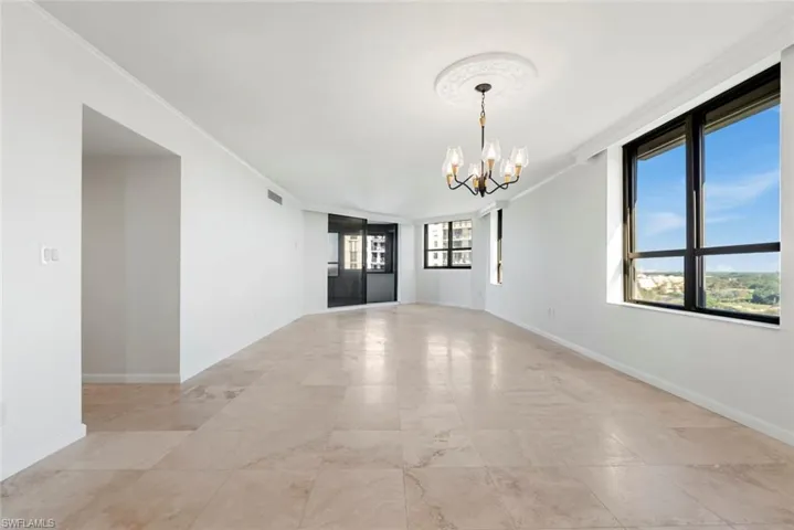 Empty room with crown molding and a chandelier