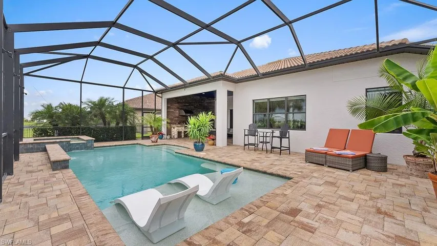 View of swimming pool with an in ground hot tub, a patio, and glass enclosure