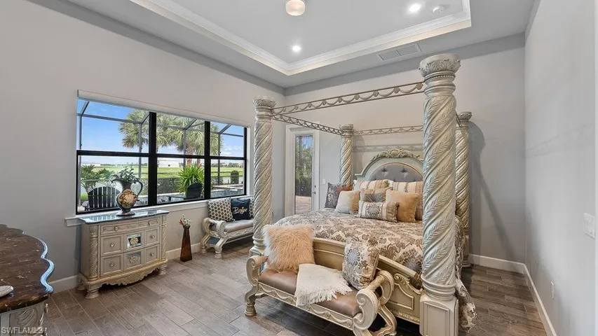 Bedroom featuring crown molding, a tray ceiling, and wood-type flooring