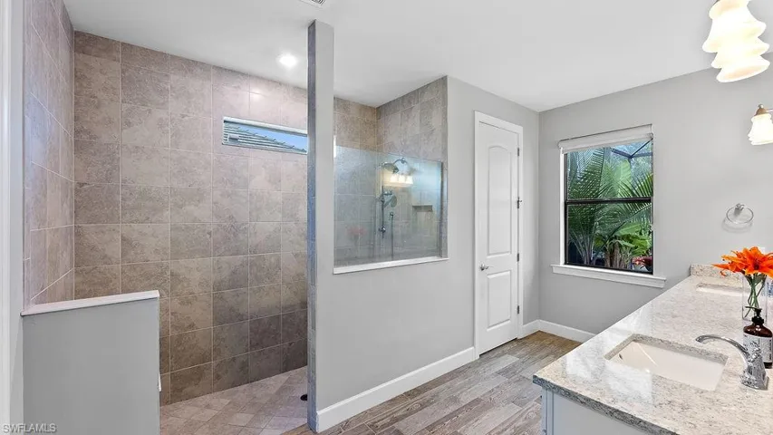 Bathroom with a tile shower, wood-type flooring, and double vanity