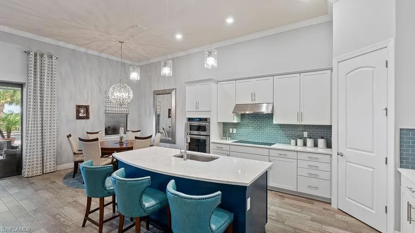 Kitchen with double oven, white cabinets, light hardwood / wood-style floors, an island with sink, and black electric stovetop