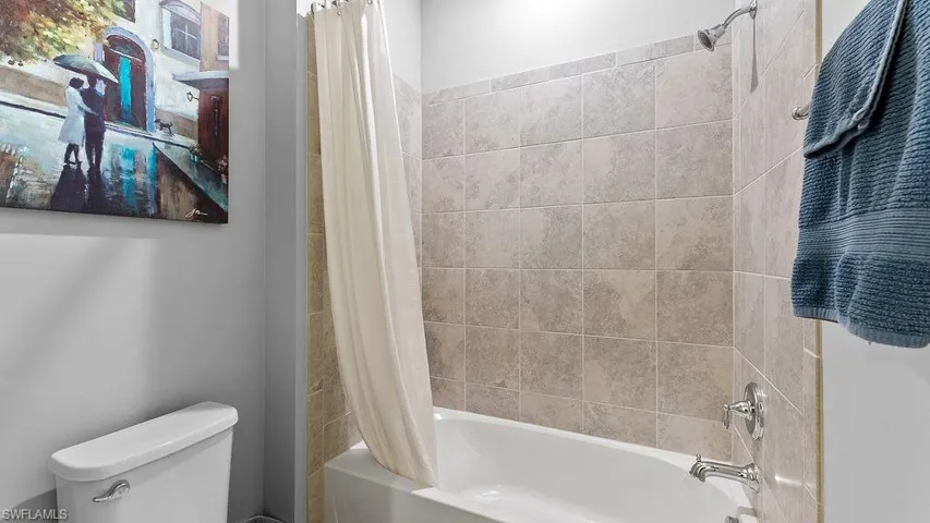 Bathroom featuring shower / tub combo with curtain and toilet