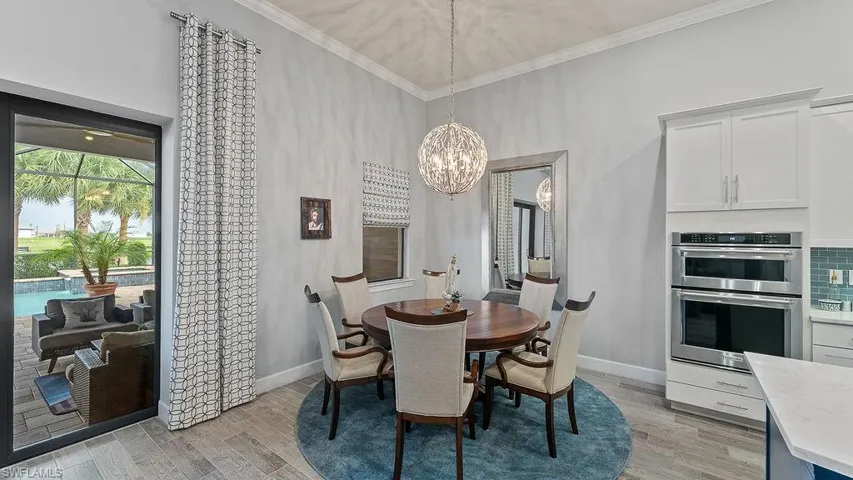 Dining area with light hardwood / wood-style floors, a towering ceiling, a chandelier, and ornamental molding