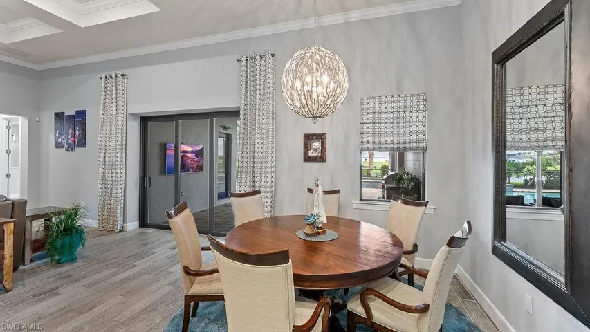 Dining space with hardwood / wood-style floors, crown molding, a notable chandelier, and a healthy amount of sunlight
