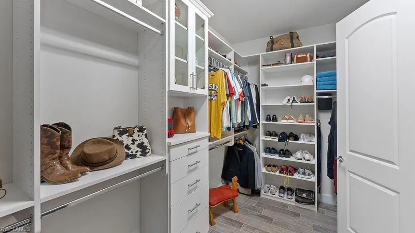 Walk in closet with light hardwood / wood-style flooring