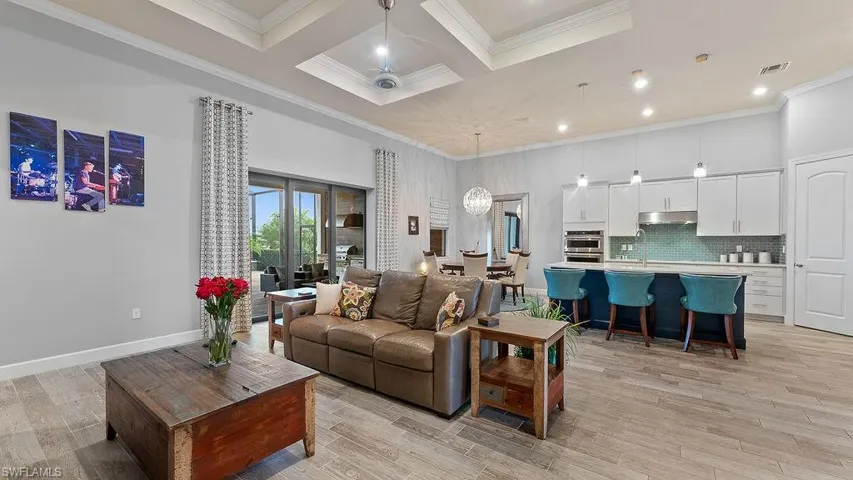 Living room with crown molding, light hardwood / wood-style flooring, and coffered ceiling