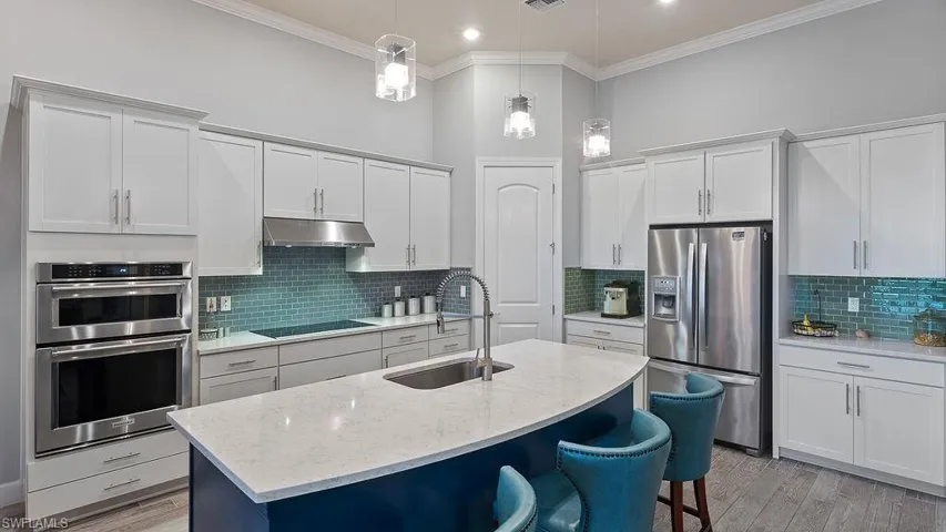 Kitchen with stainless steel appliances, pendant lighting, decorative backsplash, sink, and light hardwood / wood-style floors