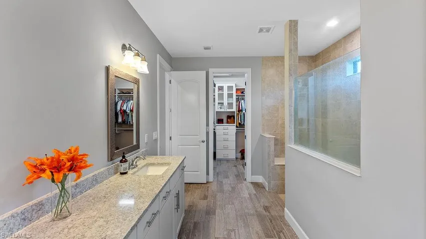 Bathroom with wood-type flooring, vanity, and a tile shower
