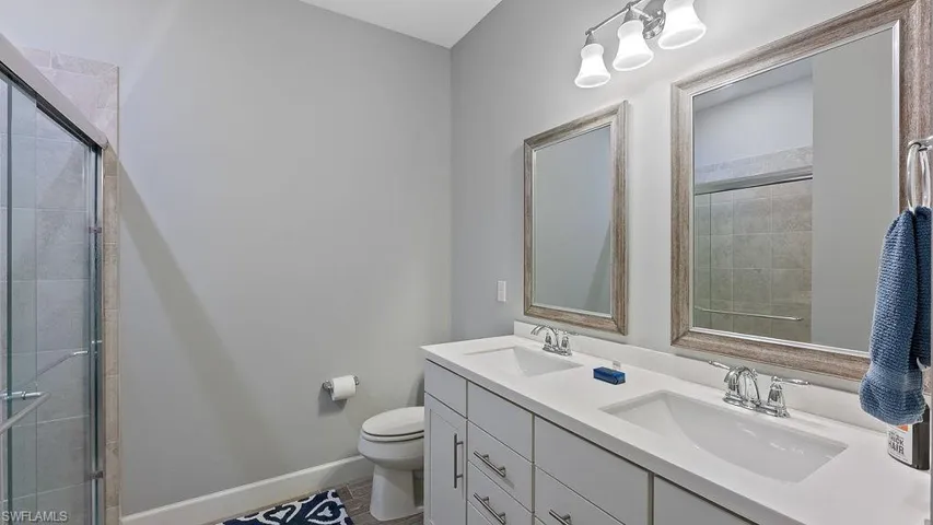 Bathroom featuring toilet, tile patterned floors, double sink vanity, and walk in shower
