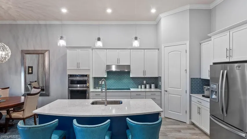 Kitchen featuring light hardwood / wood-style flooring, tasteful backsplash, white cabinets, a kitchen island with sink, and stainless steel appliances
