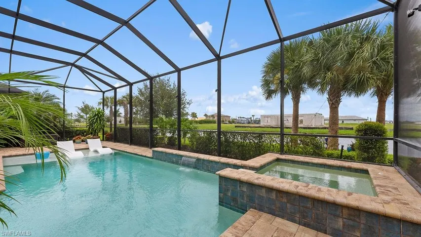 View of swimming pool with an in ground hot tub, pool water feature, and glass enclosure