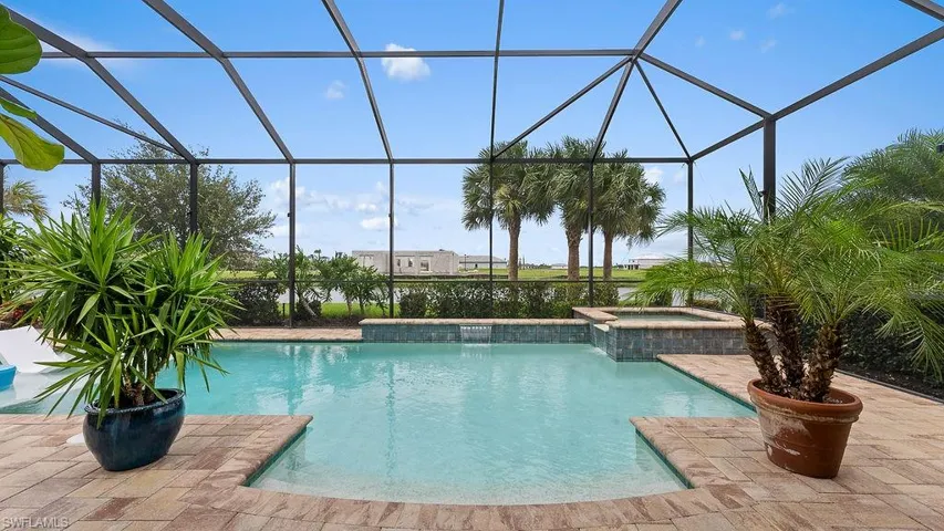 View of swimming pool with an in ground hot tub, a lanai, pool water feature, and a patio area