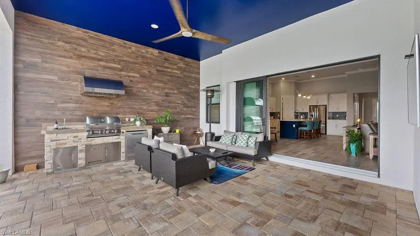 Patio at twilight featuring exterior kitchen, an outdoor living space, and a grill