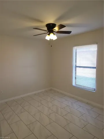 Empty room with baseboards and a ceiling fan